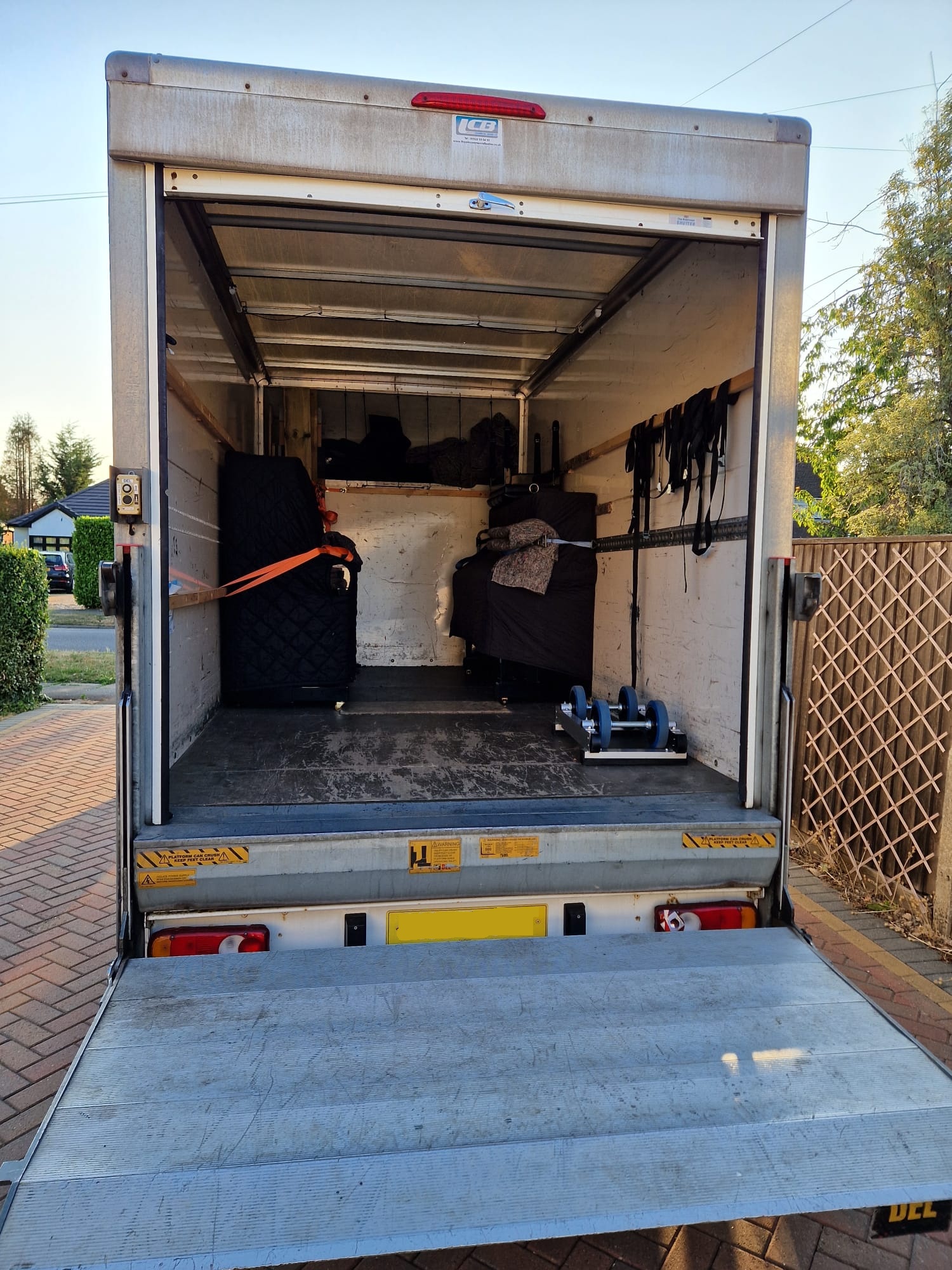 Two upright pianos securely loaded and strapped inside the back of a luton van.