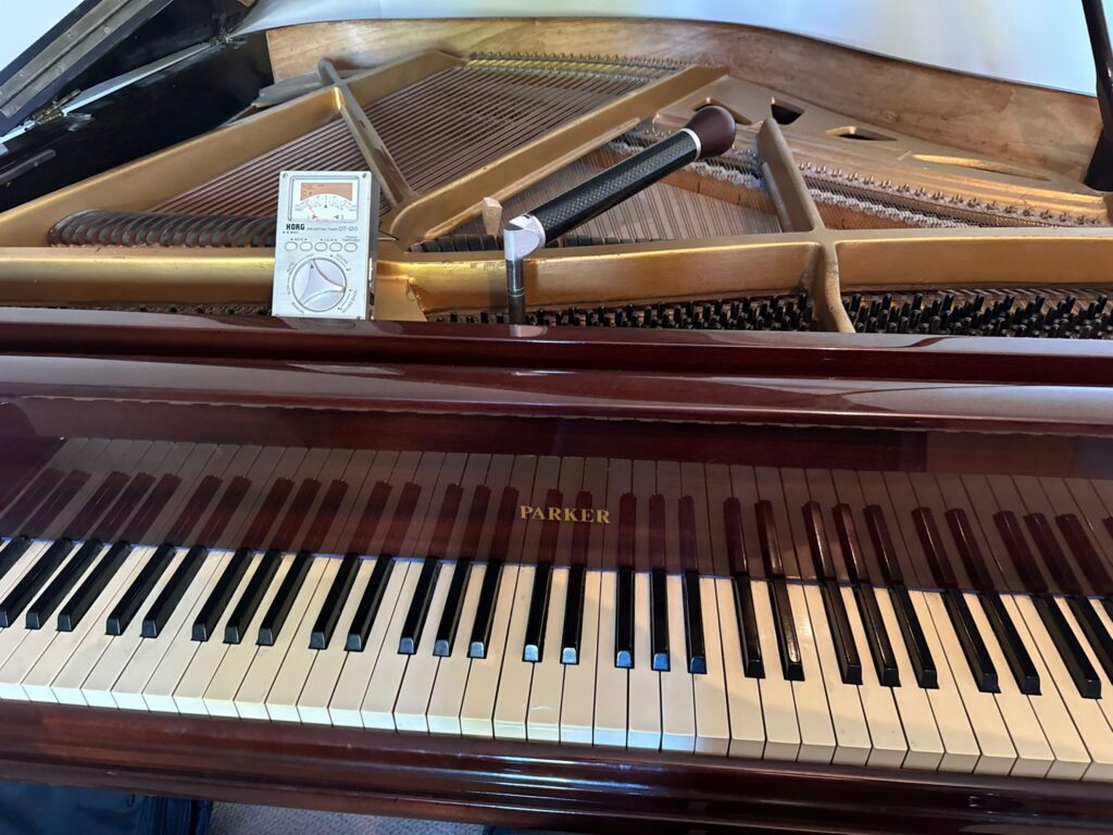 Close-up of open grand piano showing interior strings and tuning equipment.